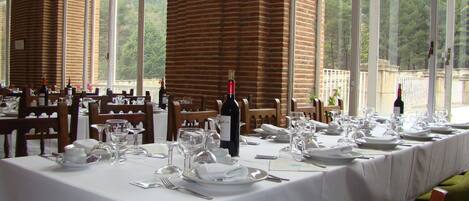 A dining area with tables set for a meal, large windows, and a brick column.