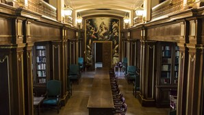 Eine lange, schmale Bibliothek mit Bücherregalen an beiden Seiten, einem zentralen Lesetisch und aufwändigen Deckenverzierungen.