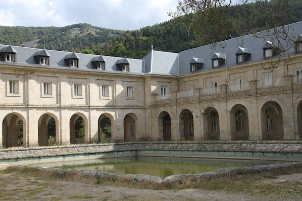 Un edificio histórico con patio central, ventanas de arco y una piscina.