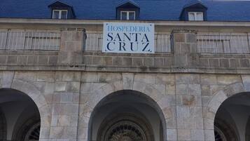 Un edificio de piedra con un letrero que dice "HOSPEDERÍA SANTA CRUZ" y un porche cubierto.