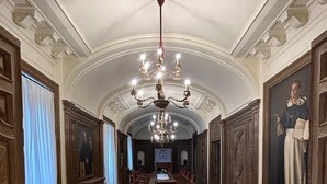 Ein prachtvoller Gang mit Holzboden, einer Chandelier und einem Esstisch mit Stühlen.