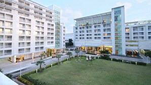 Un hotel moderno con varios pisos, un patio central y un césped bien cuidado.