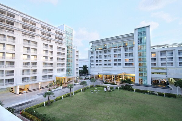 A modern hotel with multiple floors, a central courtyard, and a well-maintained lawn. - Kameo Grand Rayong Hotel & Serviced Apartments (Rayong)