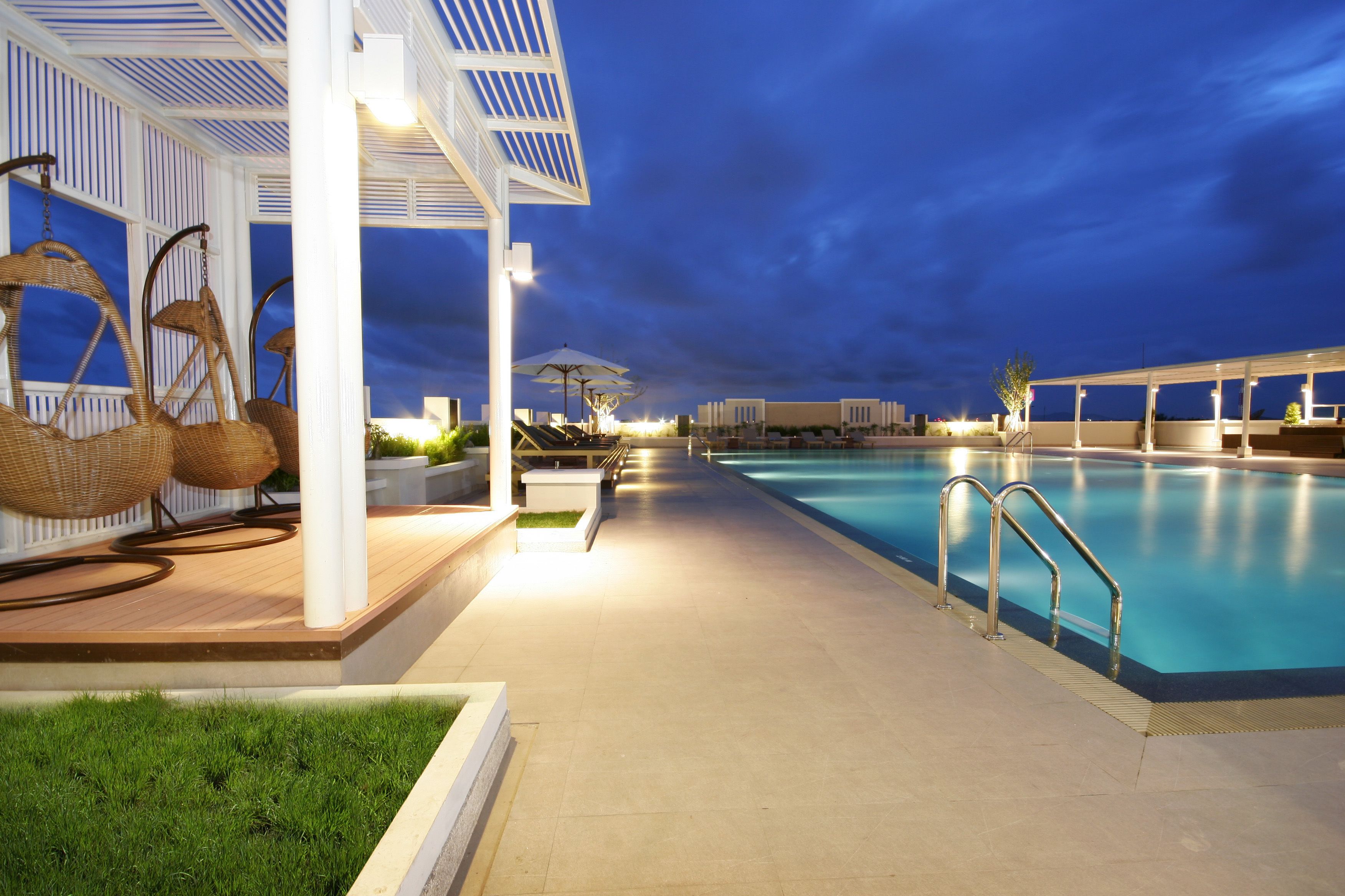 A pool area with lounge chairs and a covered seating area.