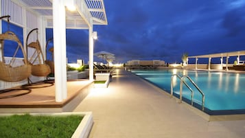 A pool area with lounge chairs and a covered seating area.