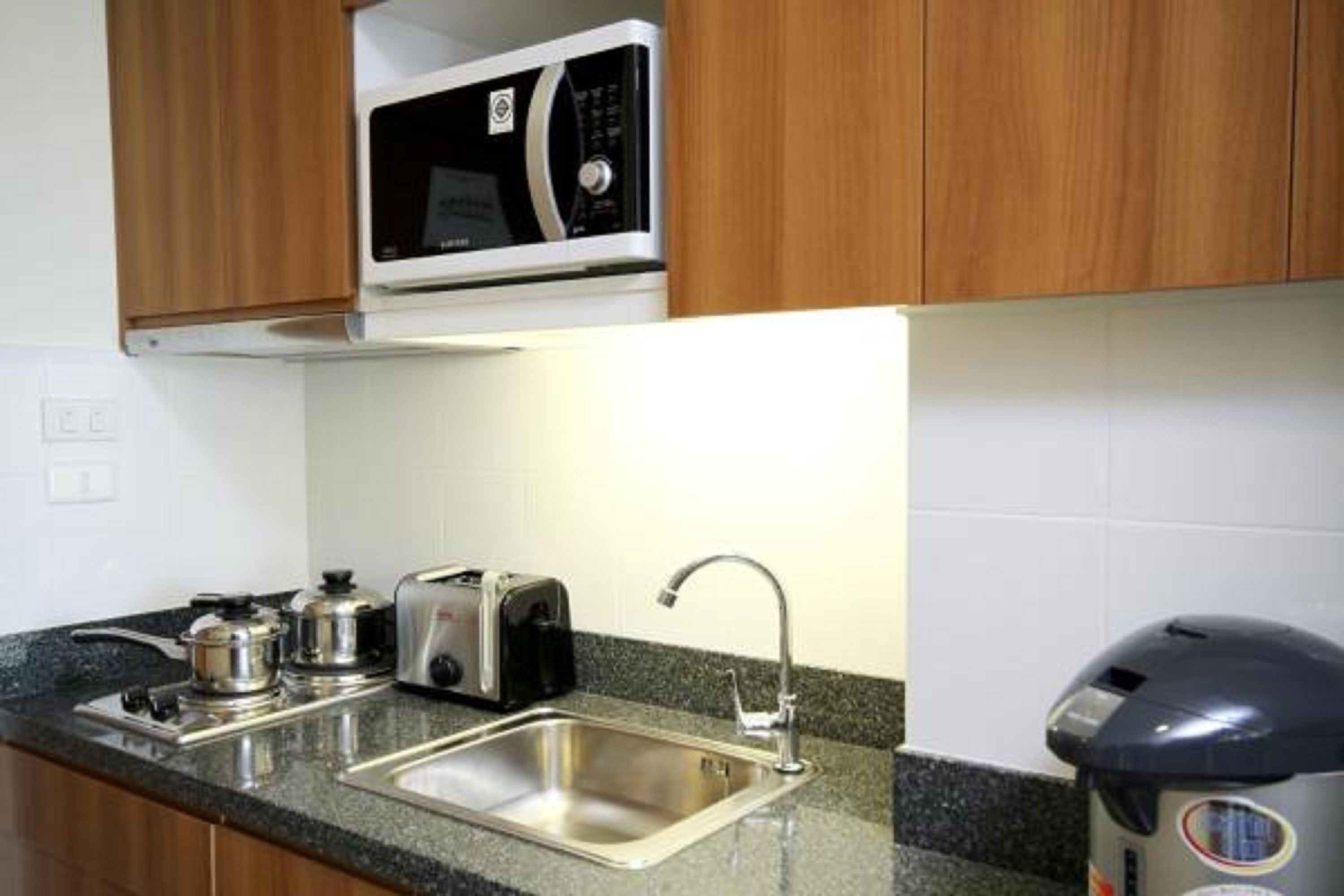 A kitchen with a stainless steel sink, a toaster, a kettle, and a microwave.