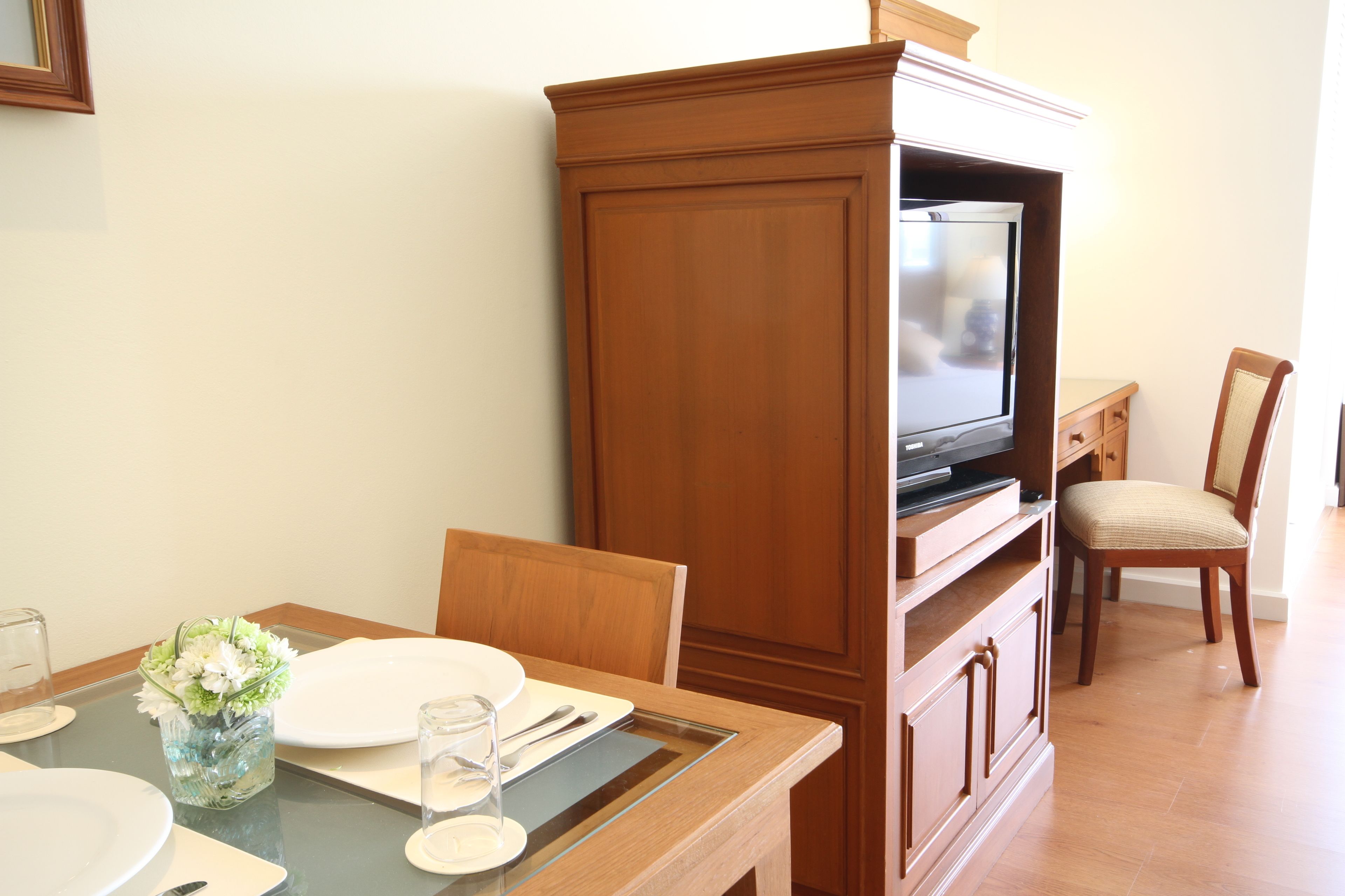 A dining area with a wooden cabinet, television, and a chair.