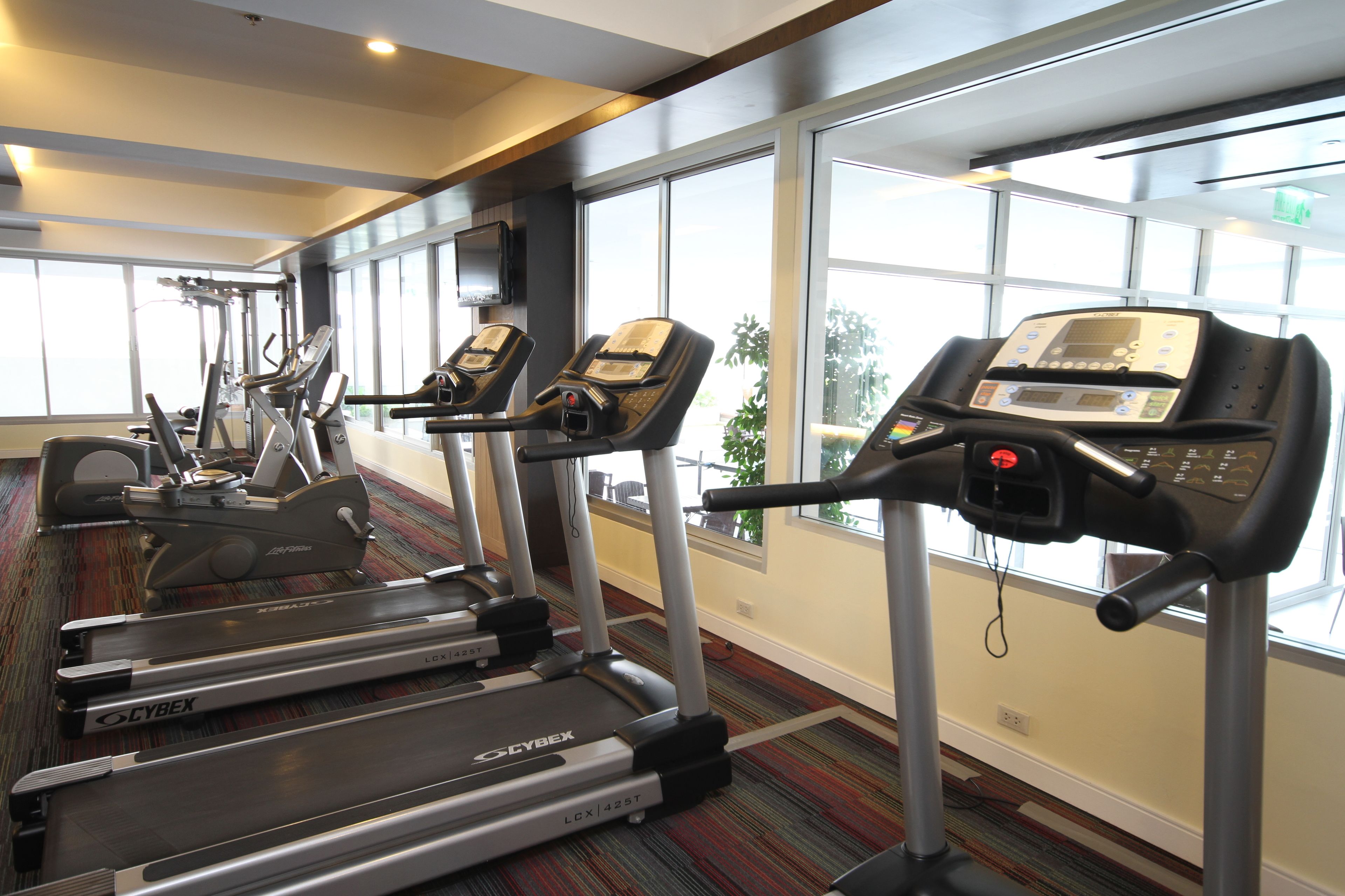 Une salle de sport équipée de tapis de course, de vélos elliptiques et d’un vélo d’appartement.