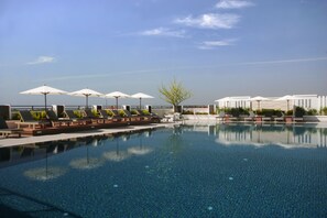 A swimming pool with lounge chairs and umbrellas, surrounded by a modern building. - Kameo Grand Rayong Hotel & Serviced Apartments (Rayong)