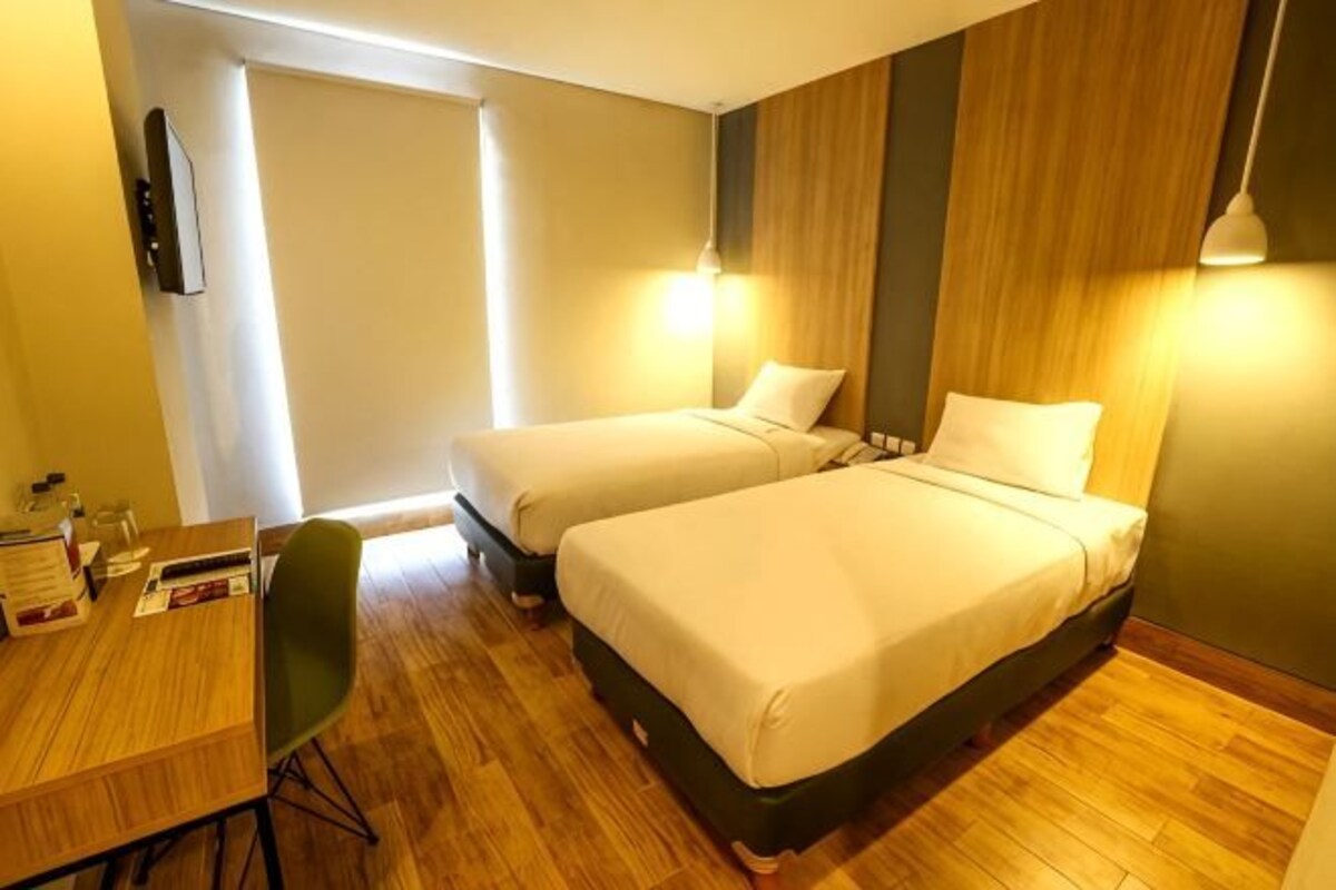 Una habitación de hotel con dos camas, un escritorio y una silla.