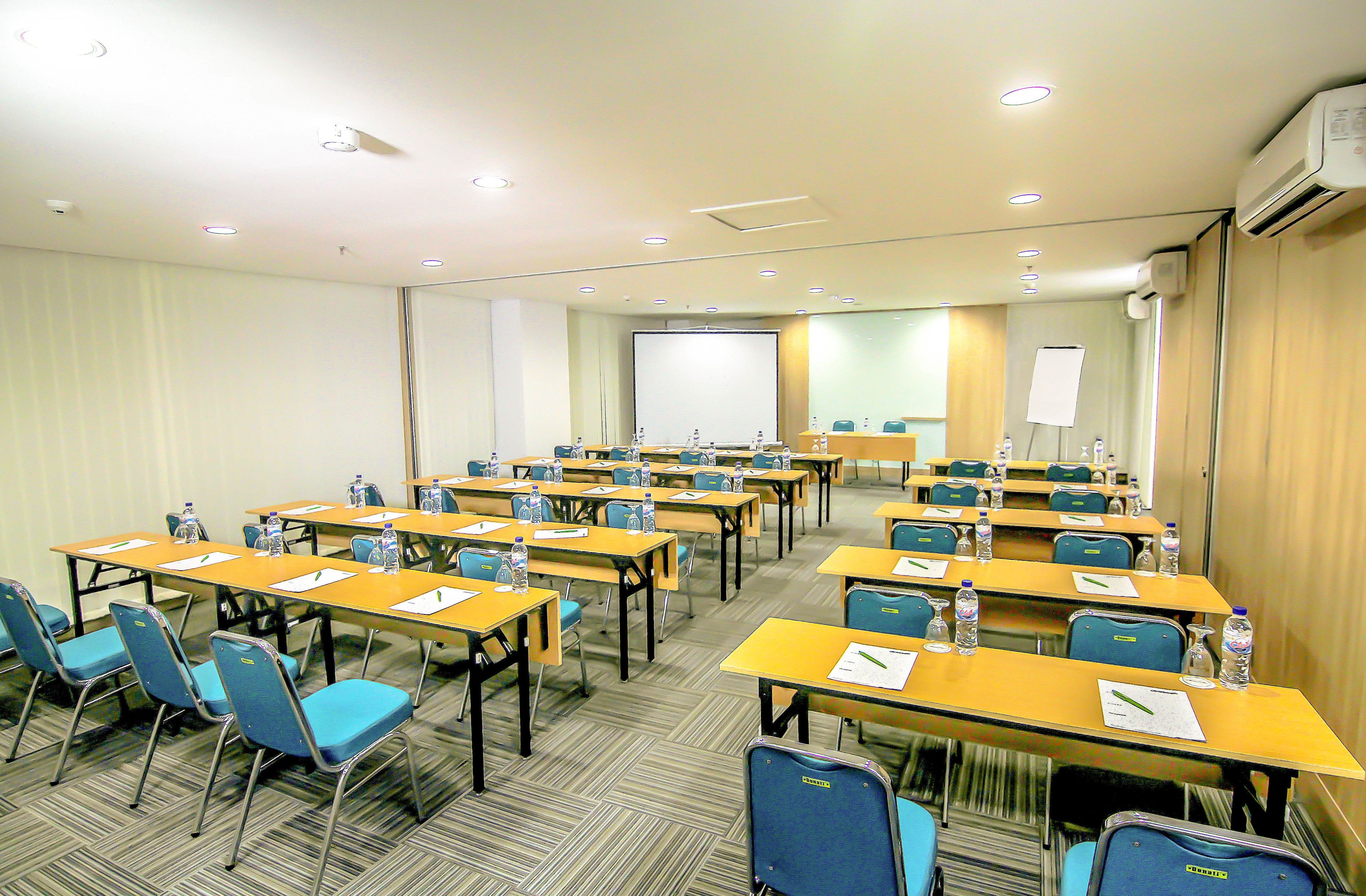 A conference room with multiple tables and chairs, equipped with water bottles and papers.