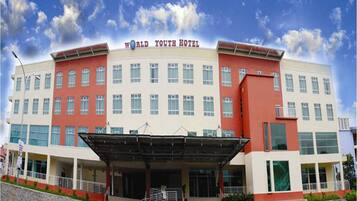 A large hotel with a red and white facade, multiple floors, and a covered entrance area.