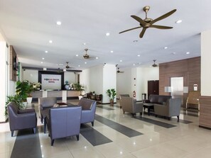 Et hotellobby med moderne møbler, ventilatorer i loftet og en receptionsdisk.