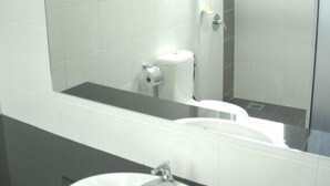 A bathroom with a white sink, a mirror, and a toilet. - Petanak Lodge (Kuching)