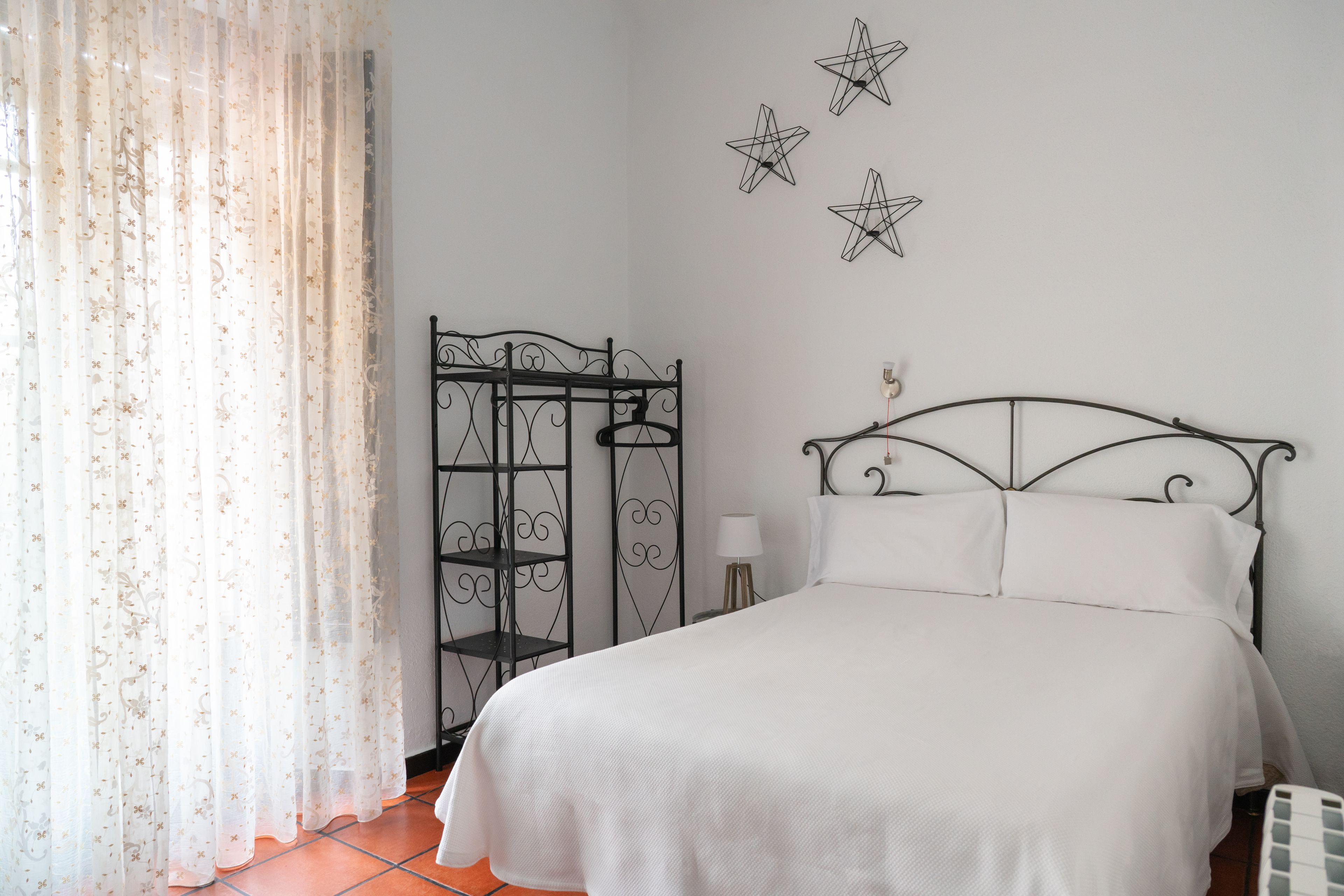 Un dormitorio con una cama, una estantería metálica y decoraciones en forma de estrella en la pared.