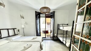 Habitación de hotel con dos camas, una lámpara colgante, vistas al balcón exterior y una puerta que da al balcón.