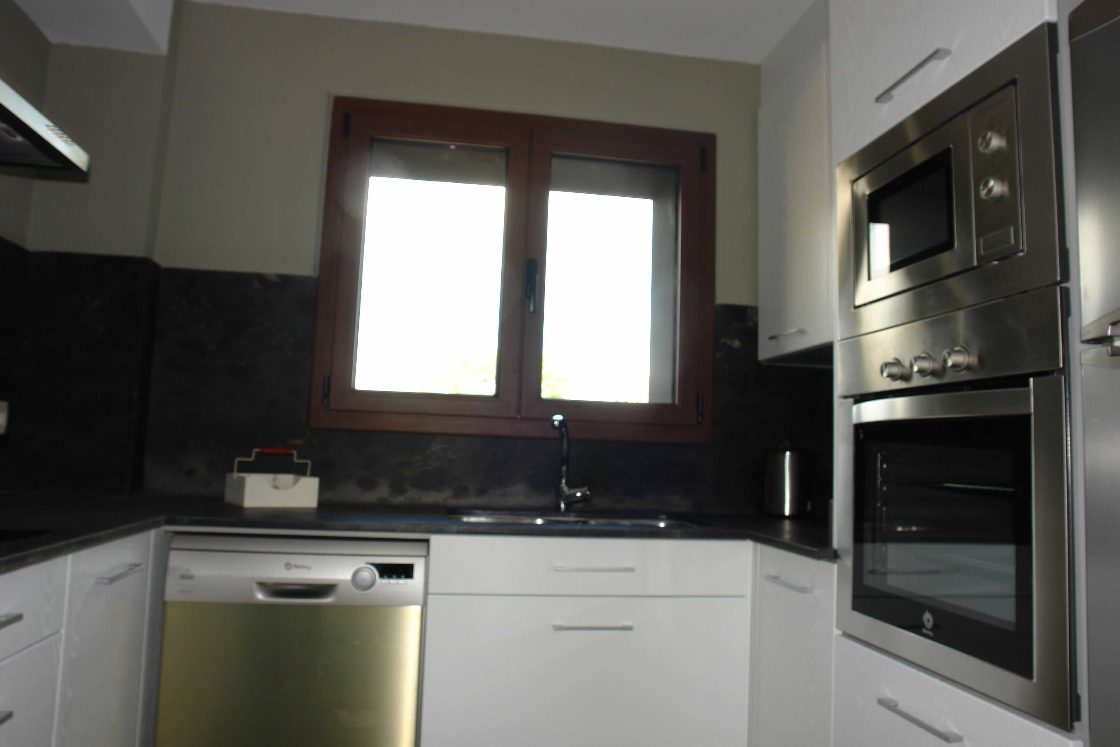 A kitchen with a dishwasher, double sink, and stainless steel appliances including an oven and microwave.