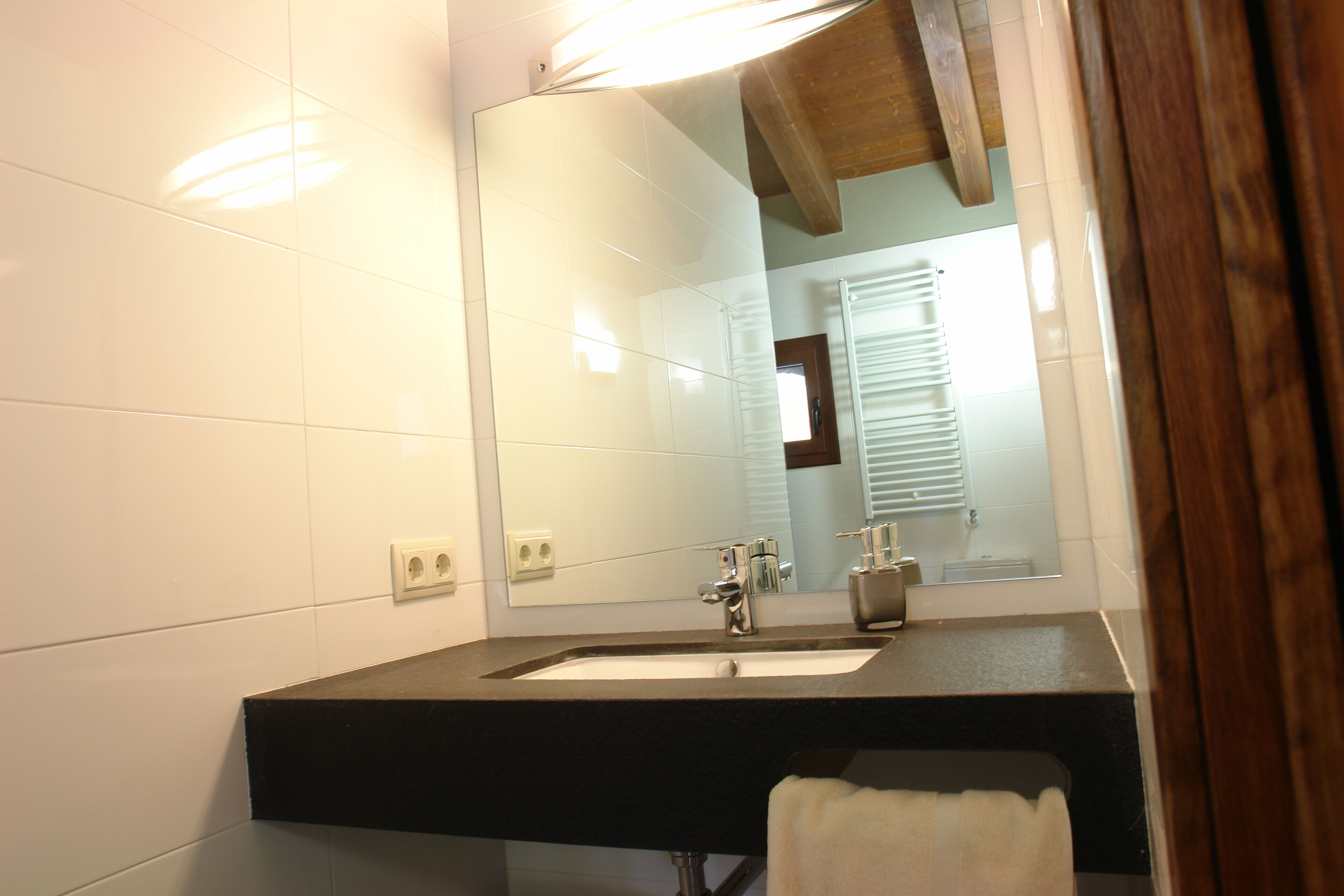 Une salle de bain avec un comptoir noir, un lavabo blanc et un grand miroir.