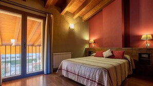 Une chambre dotée d’un grand lit, de deux lampes de chevet, d’une tête de lit en bois et donnant sur un espace extérieur grâce à une porte coulissante.