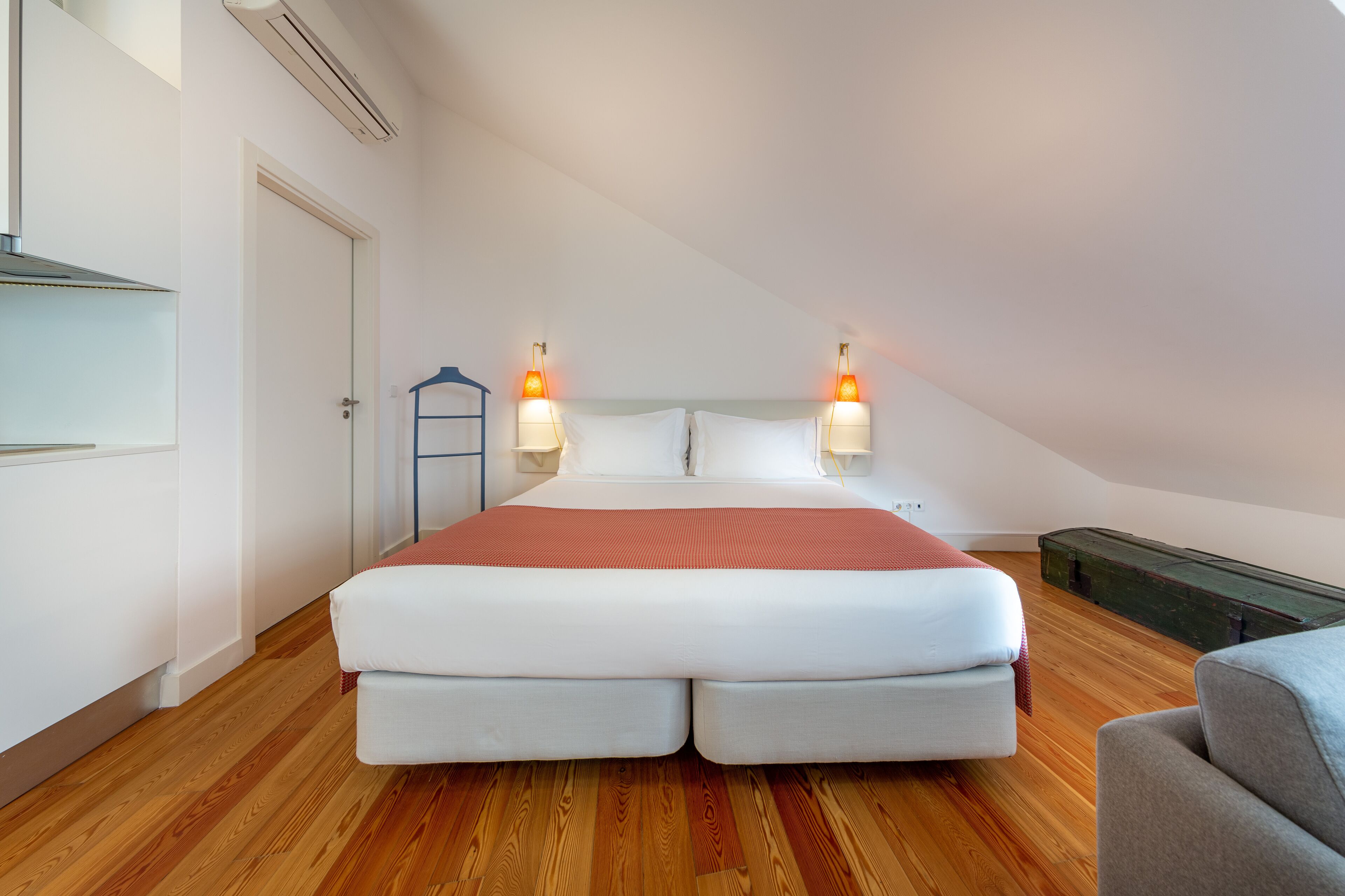Une chambre avec un grand lit, deux lampes de chevet, un radiateur et une armoire.