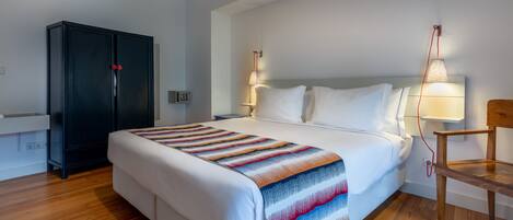 Une chambre d’hôtel avec un grand lit, une armoire, un bureau et une chaise.