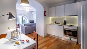 A modern kitchen with white cabinets, a built-in oven, and a dining area with a table set for a meal.