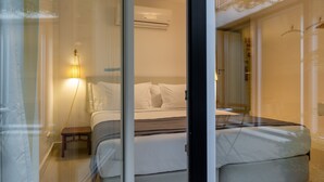 A modern bedroom with a bed, bedside table, and a wall-mounted air conditioner.
