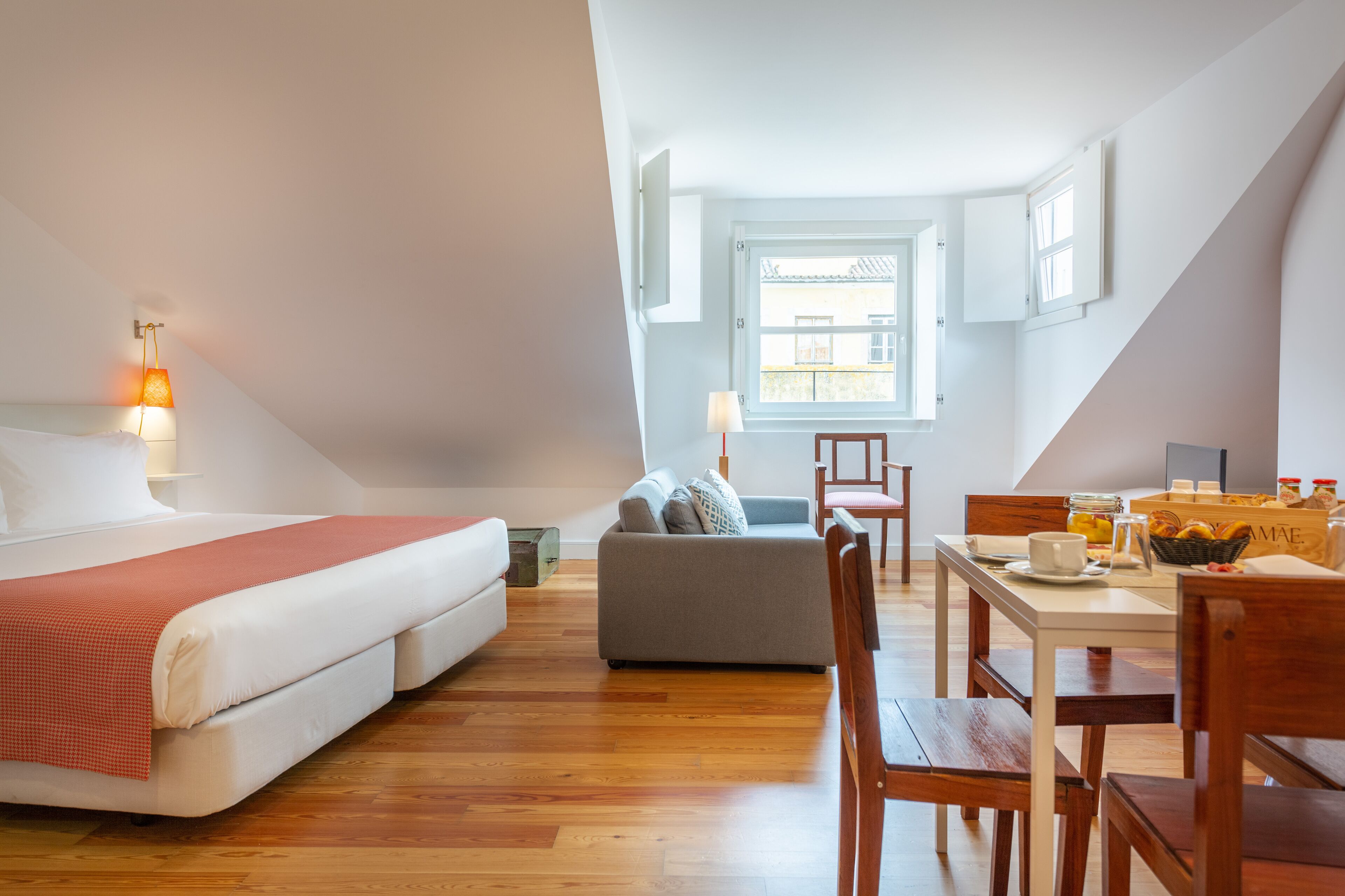 Un dormitorio con cama, sofá, mesa de comedor con sillas y ventana con cortinas.