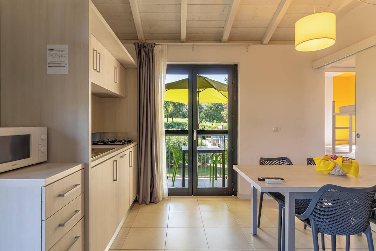 Een moderne keuken met een magnetron, kastjes en een schuifdeur naar een balkon met een gele parasol.