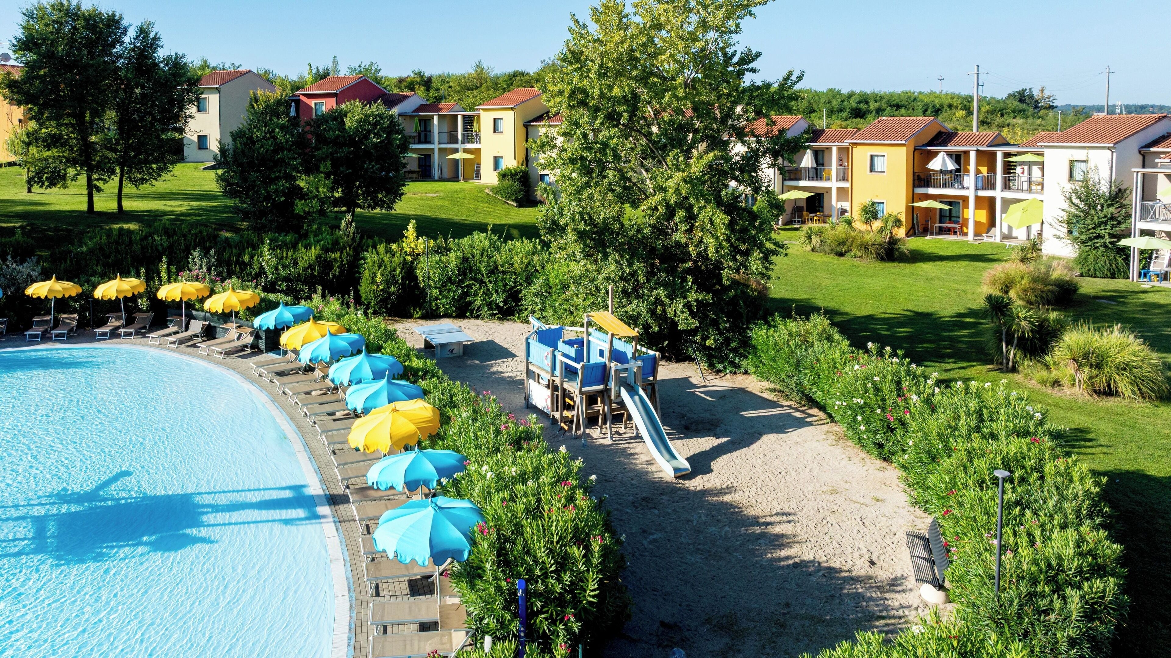 Un resort con piscina, lettini prendisole e uno scivolo.