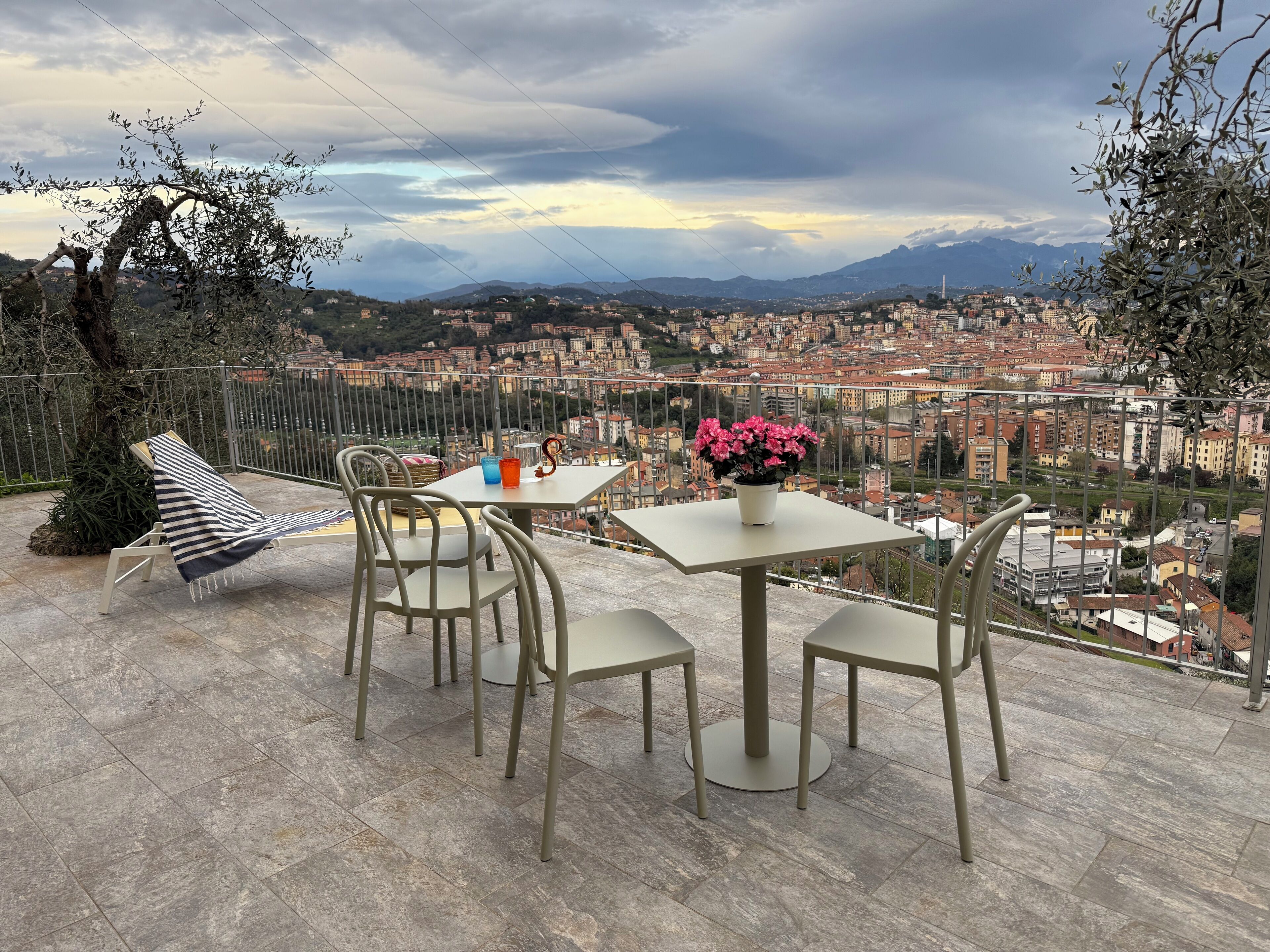 Eine Terrasse mit Tisch und Stühlen, einem Blumentopf und einem gestreiften Kissen.