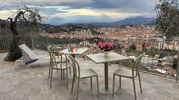 Une terrasse avec une table et des chaises, un pot de fleurs et un coussin à rayures.