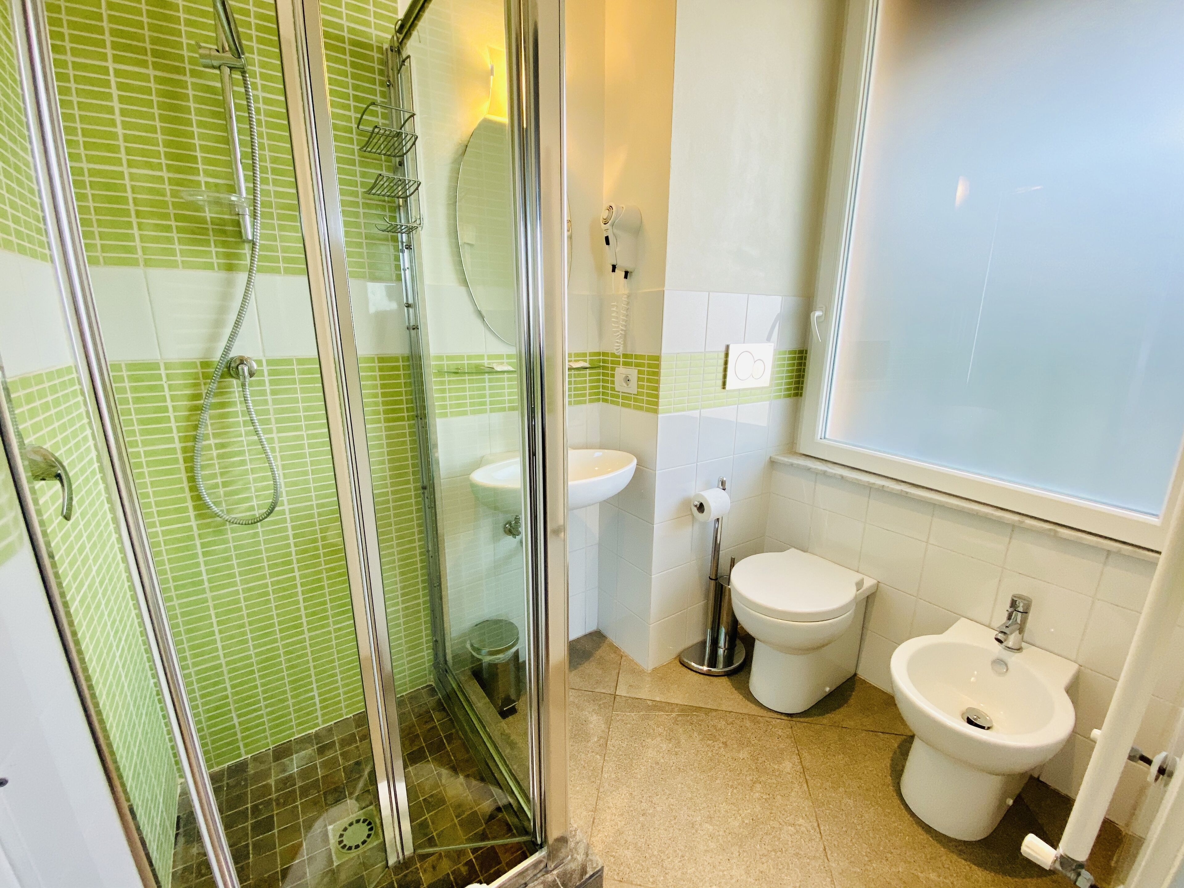 Un baño con ducha acristalada, lavabo, inodoro y bidé.