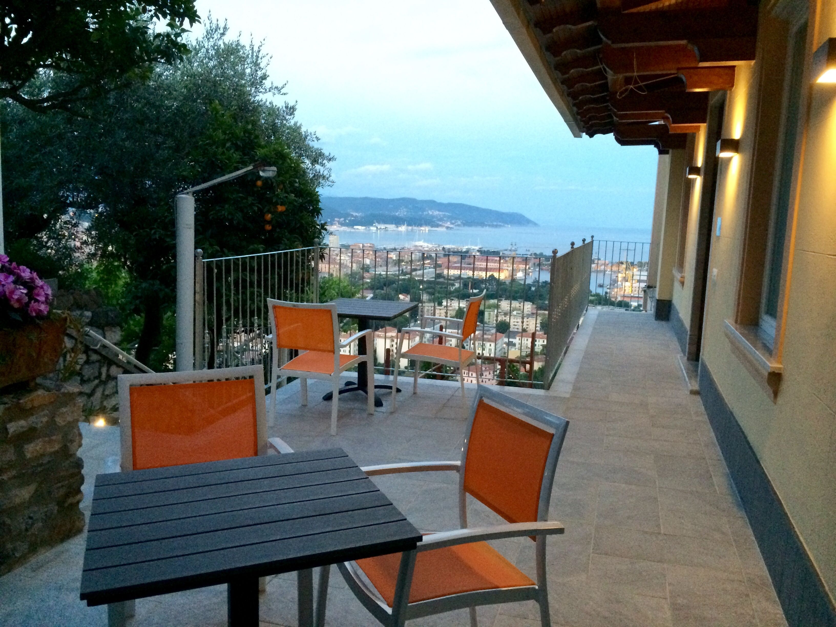An outdoor patio with a table and chairs, overlooking a cityscape and the sea.