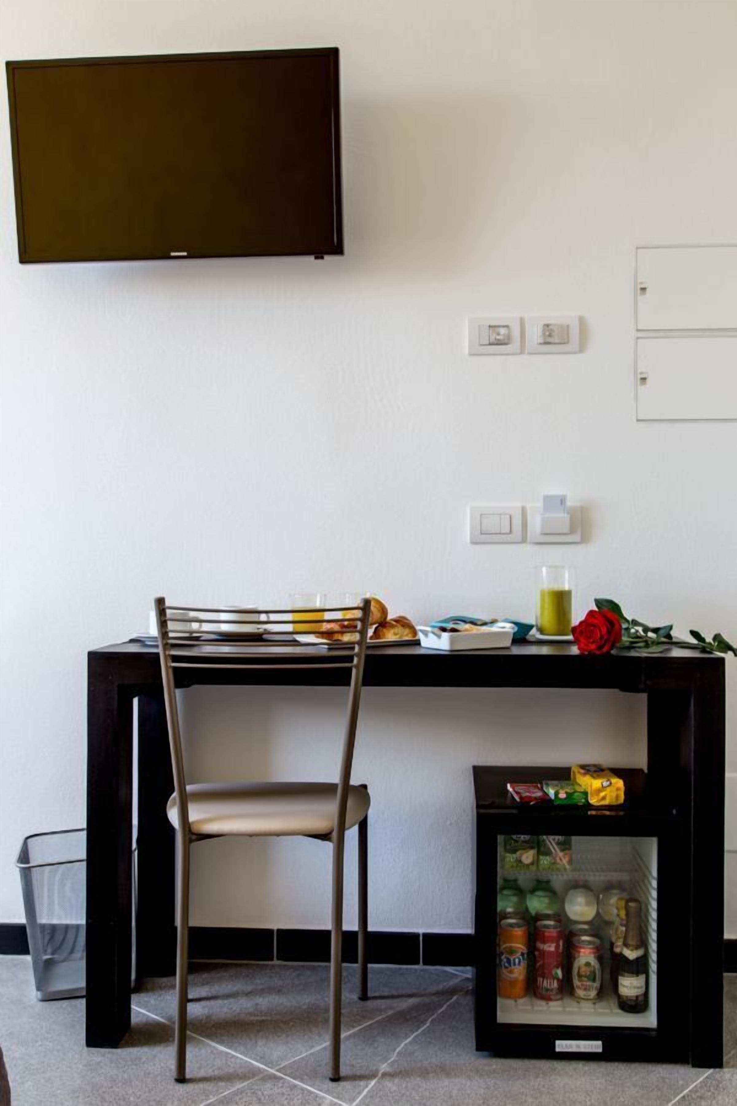 Un comedor con una mesa, una silla y un refrigerador pequeño con bebidas.