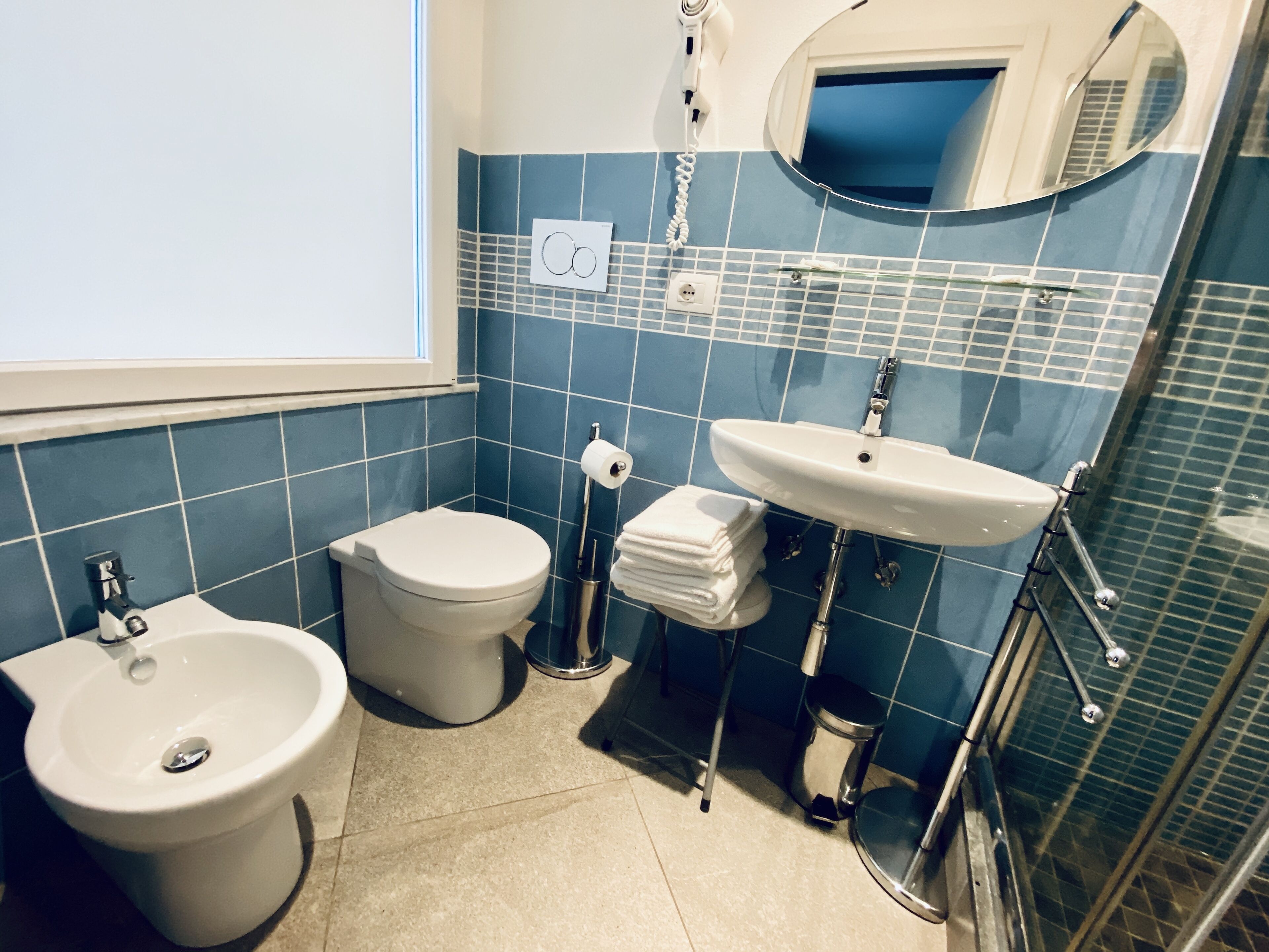 A bathroom with a bidet, toilet, sink, and a mirror.