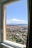 Vista urbana a través de una ventana con una persiana entreabierta.