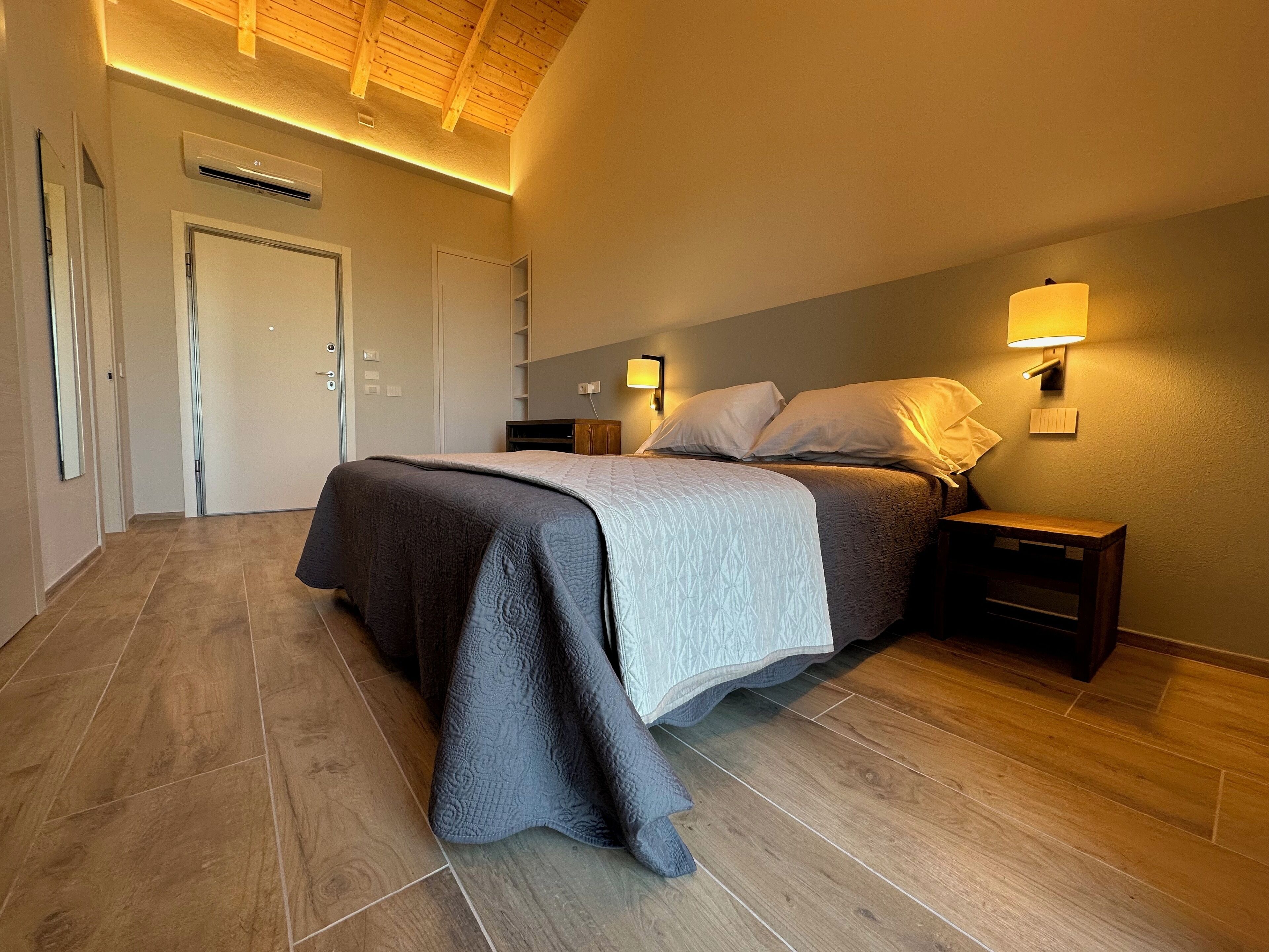 A bedroom with a bed, bedside tables, a wall-mounted lamp, and a ceiling fan.