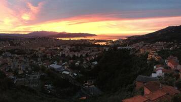 Paesaggio urbano al tramonto con edifici e uno specchio d'acqua in lontananza.