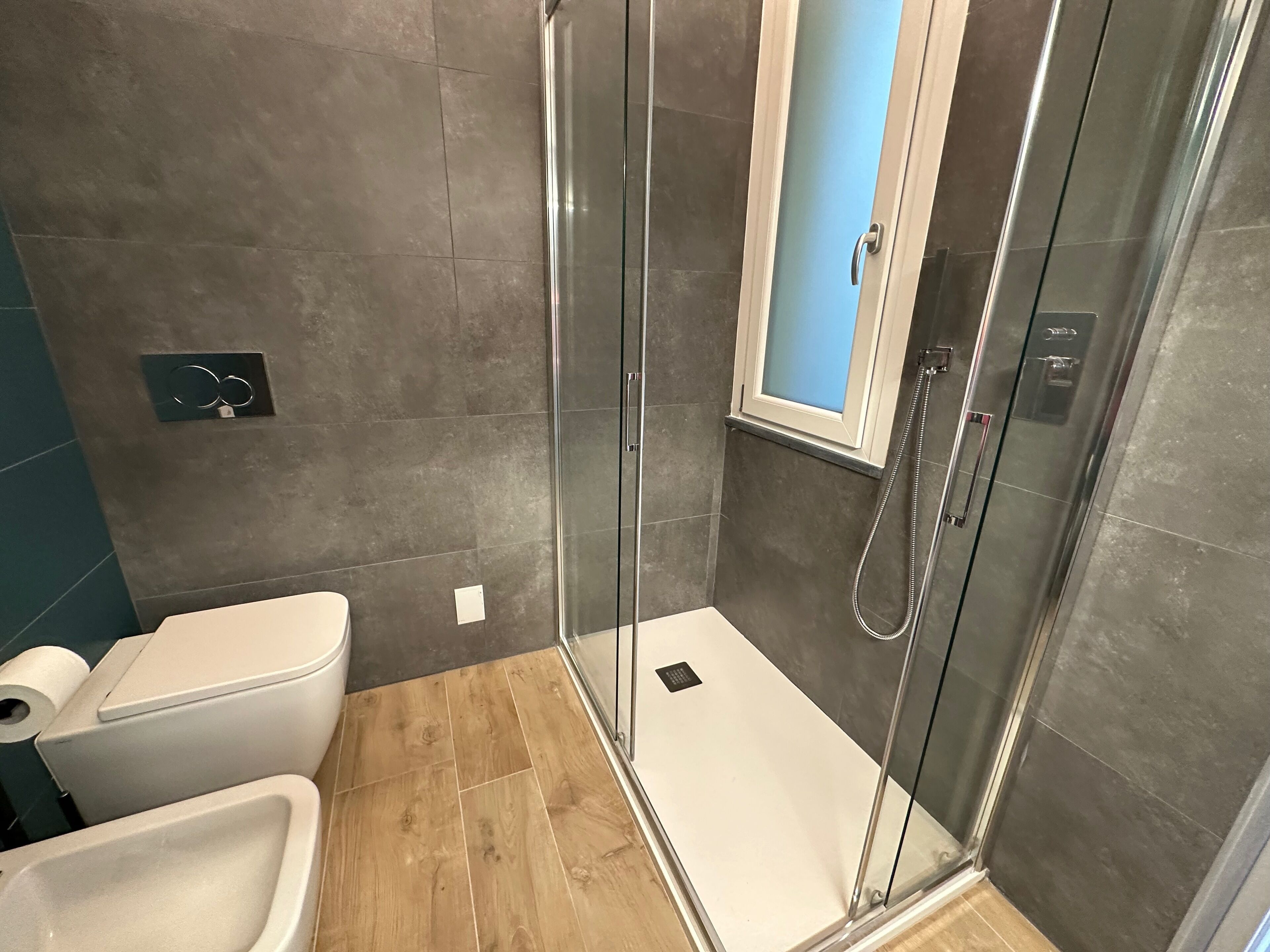 Un baño moderno con ducha envuelta en vidrio, inodoro y lavamanos.
