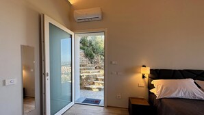 A bedroom with a bed, bedside table, and a view of a stone staircase leading outside.