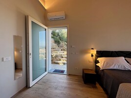 Un dormitorio con cama, mesita de noche y vistas a una escalera de piedra que da al exterior.