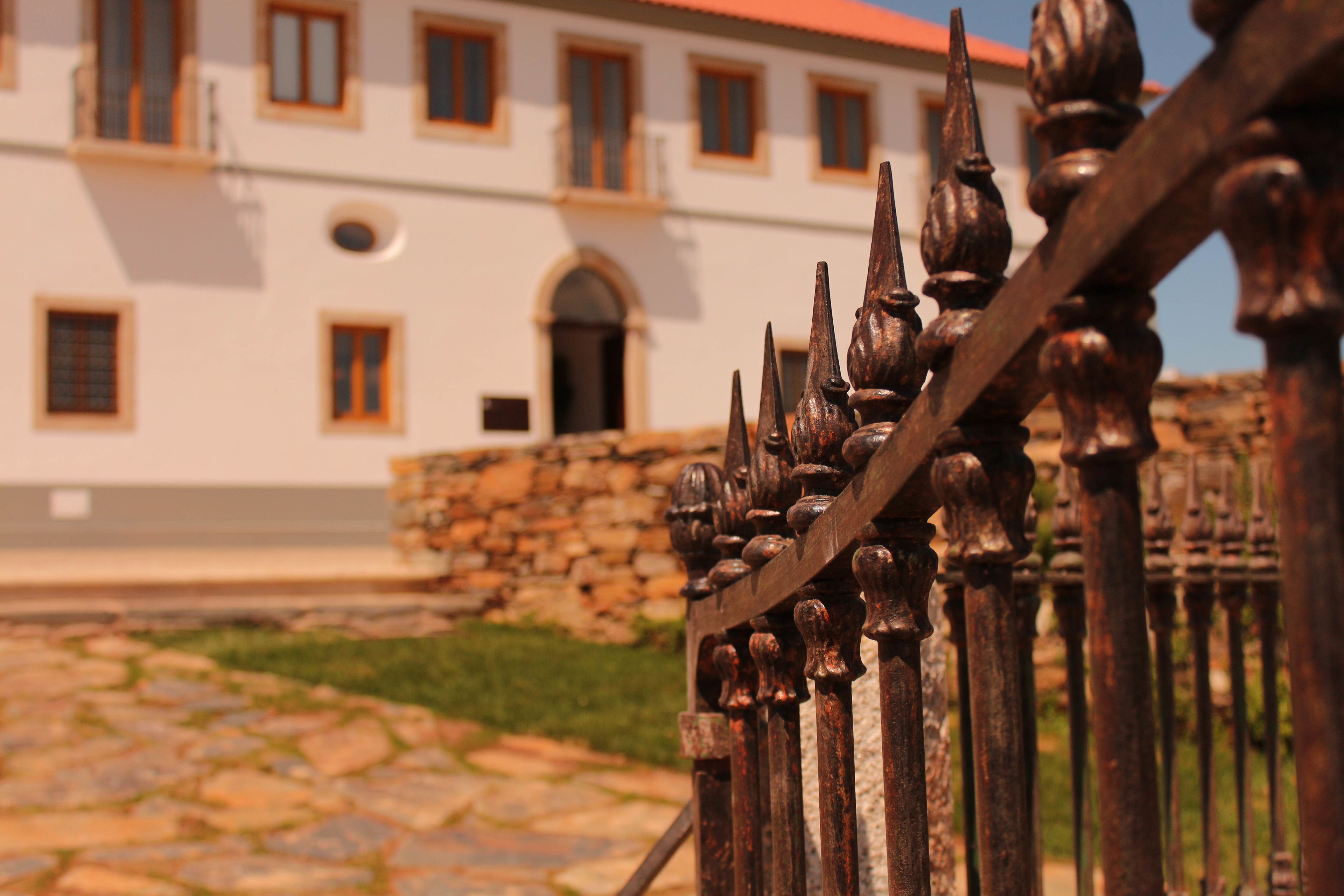 Un patio empedrado con un edificio blanco, ventanas de arco y techo rojo.
