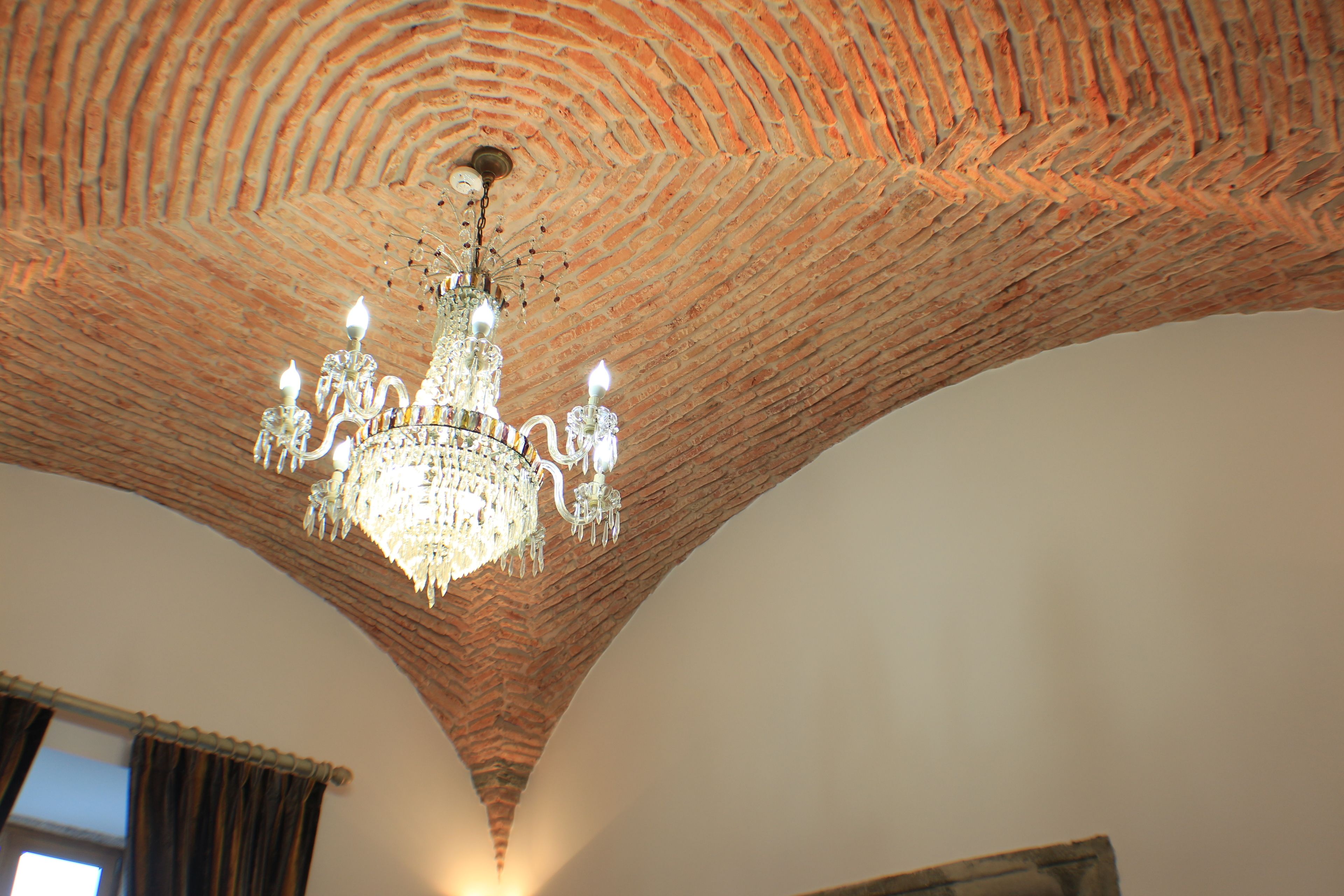 A room with a brick ceiling and a chandelier.