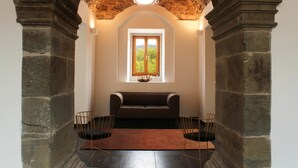 A room with a stone archway, a wooden bench, and two chairs. - Convento da Serta Hotel (Serta)