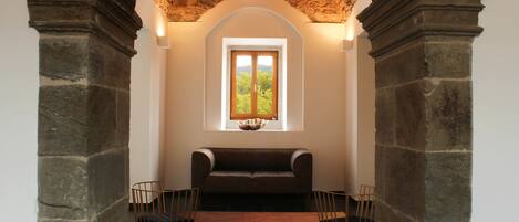 A room with a stone archway, a wooden bench, and two chairs.