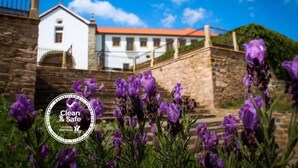 A white building with a red roof, a stone staircase, and purple flowers in the foreground. - Convento da Serta Hotel (Serta)