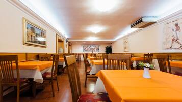 A restaurant with multiple tables and chairs, a ceiling fan, and artwork on the walls.
