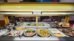 A buffet with various food items including fruits, vegetables, and cheeses.