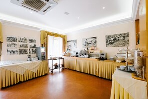 Quarto de hotel com área de refeições, incluindo buffet, máquina de café e geladeira.
